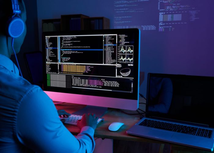 Programmer in headphones checking his code on computer screen